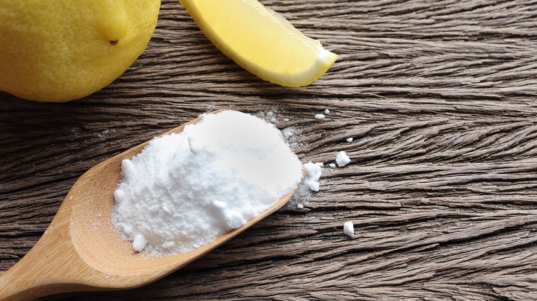 baking soda on a wooden spoon with lemons nearby