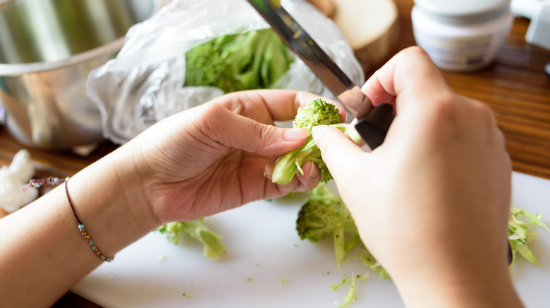 Person peeling broccoli stems