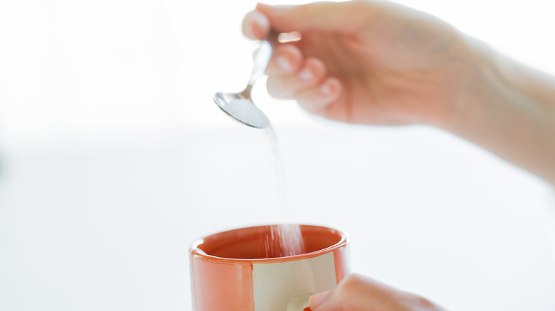 woman pouring sugar into mug