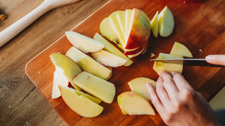 Person slicing apples on cutting board