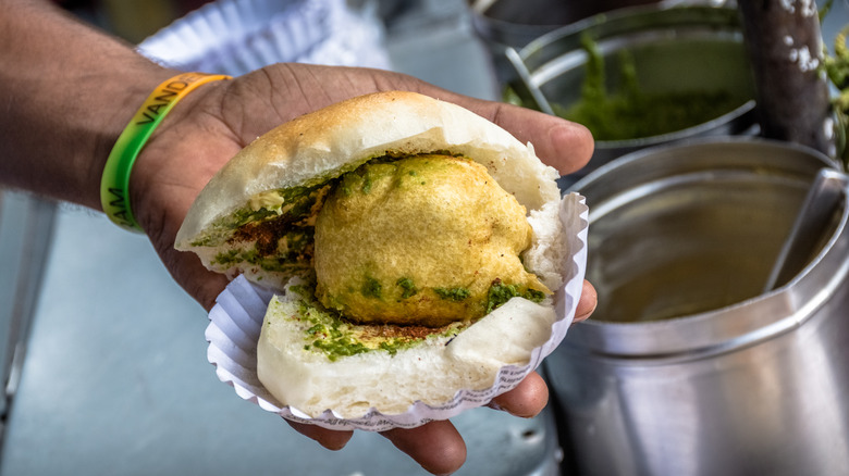 Indian street food vendor holding vada pav