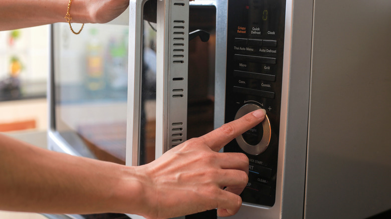 woman setting the timer on a microwave