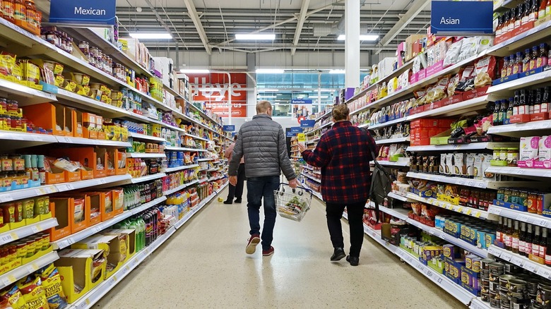 Two people walk down an aisle in Walmart