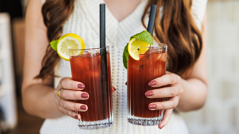 woman holding two glasses of iced tea