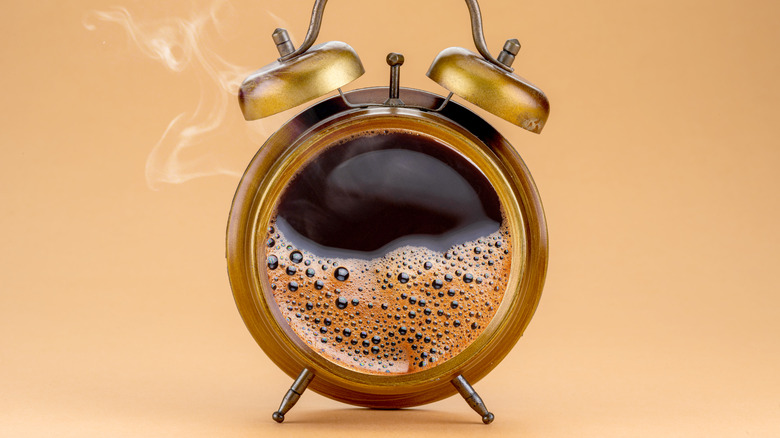 old alarm clock filled with hot coffee tan background