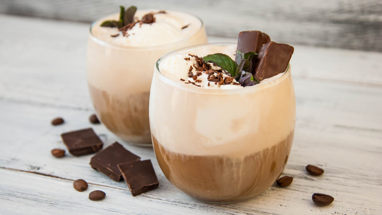 Frothed chocolate-topped lattes in glass tumblers wooden table