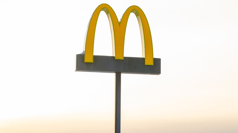 A tall McDonald's sign against a yellow-gray sky