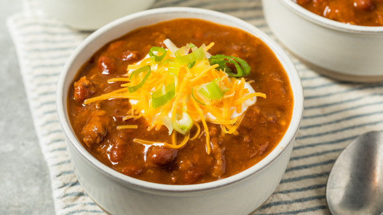 Bowl of chili topped with sour cream, cheese and green onion