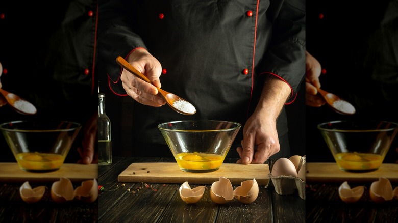 Chef adding salt to eggs