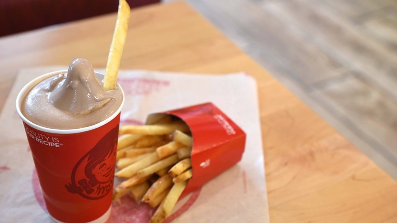 Fry sticking out of a Wendy's Frosty on restaurant table next to more fries