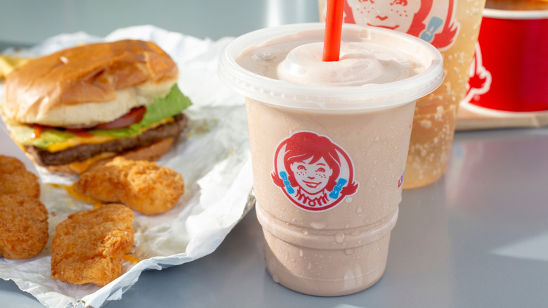 Frosty in a transparent cup next to Wendy's nuggets and a burger.