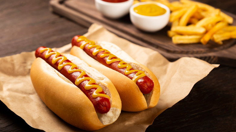 Hot dogs on a bun served with mustard, ketchup, and fries