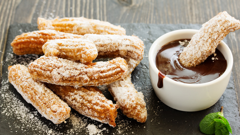 Churros getting dipped in chocolate sauce