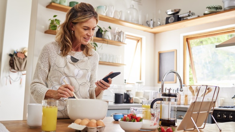 woman cooking with recipe on phone