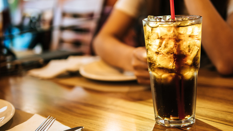 A large soda with ice, on a restaurant table