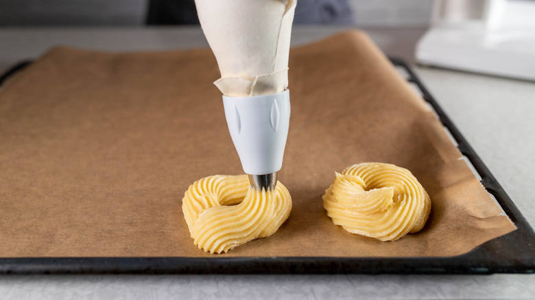 Crullers being piped onto parchment