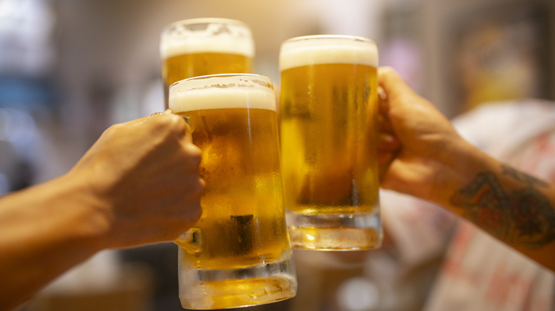 three beer mugs and hands toasting