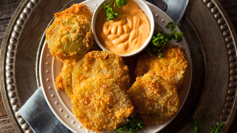 Plate of fried green tomatoes served with a pale orange dipping sauce