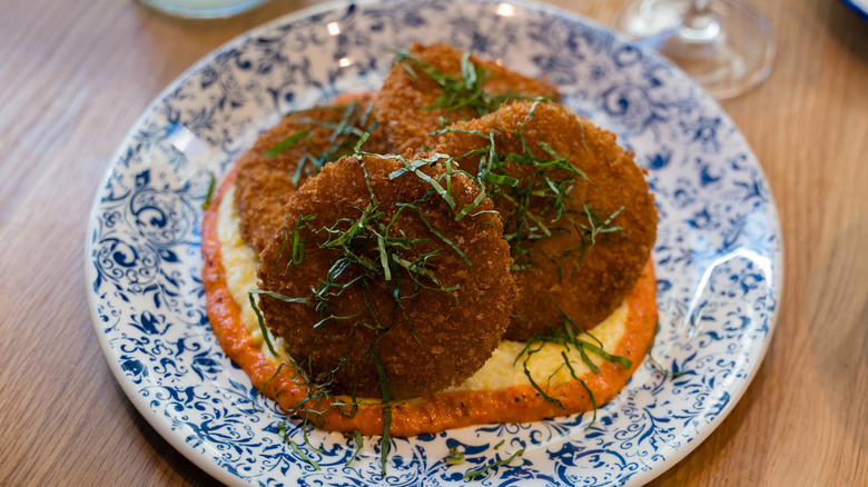 Tupelo Honey panko-crusted fried green tomatoes with basil, roasted red pepper sauce, and heirloom grits with goat cheese