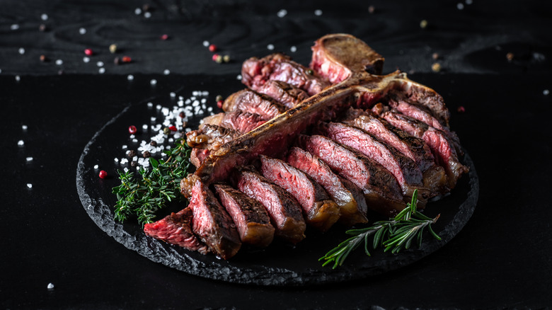 Sliced t-bone steak with salt, pepper, and rosemary