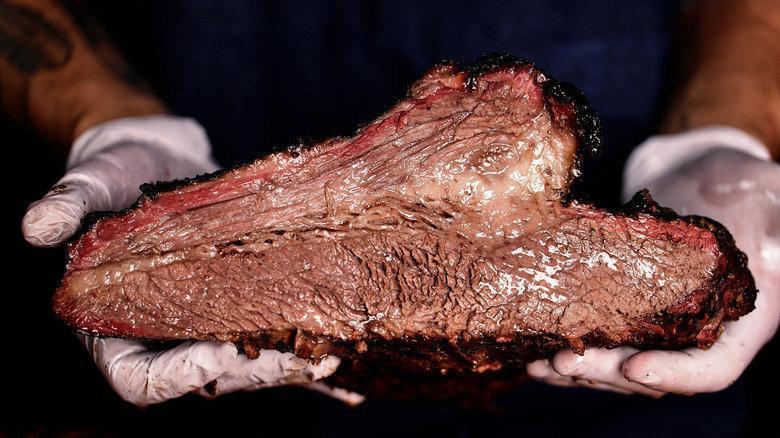 hands holding smoked brisket