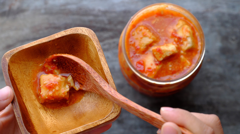 Person spooning fermented tofu onto plate