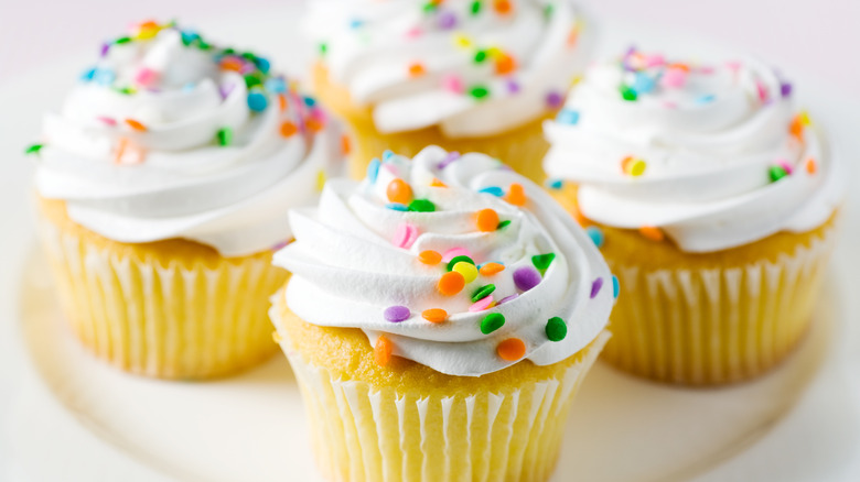 four cupcakes with colorful sprinkles