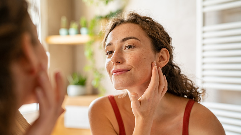 woman checking skin in mirror