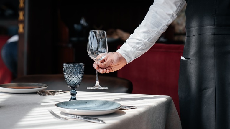 waiter placing restaurant table setting