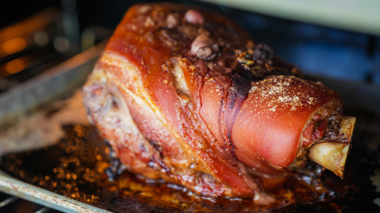 Roasted pork shoulder in a roasting tray in the oven