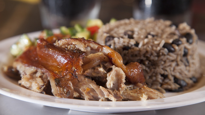 Pernil pieces with a side of rice and beans