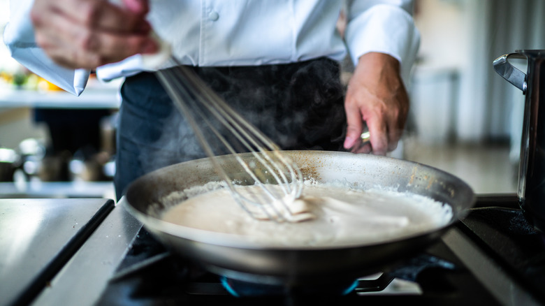 A person making a white sauce