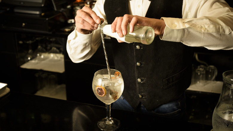 bartender pouring soda down bar spoon