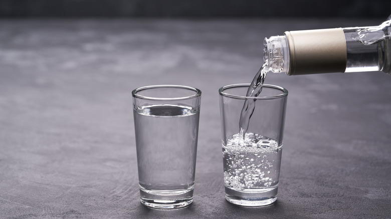 Pouring two glasses of vodka on gray surface