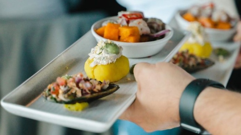 a server holds a plate containing different foods