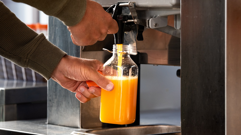 man filling bottle with fresh squeezed orange juice