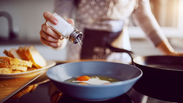 Woman adding salt to eggs