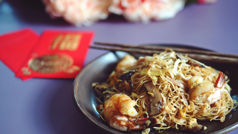 Plate of longevity noodles beside Lunar New Year envelopes