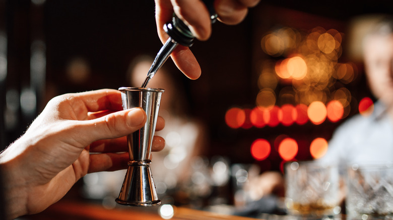 Bartender uses a jigger