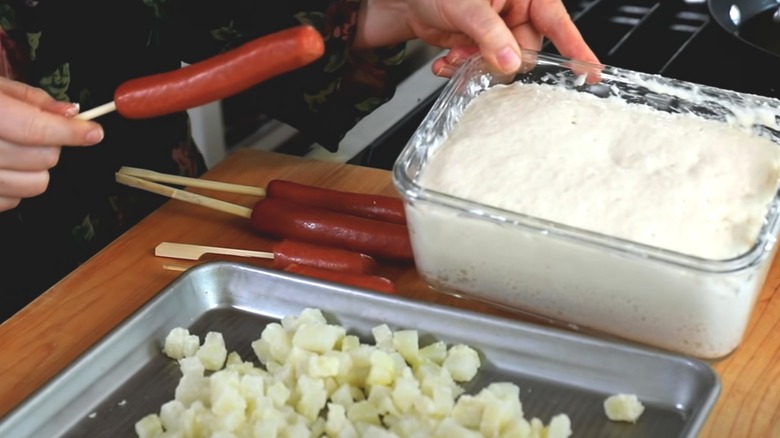 Hot dogs being battered into Korean corn dogs