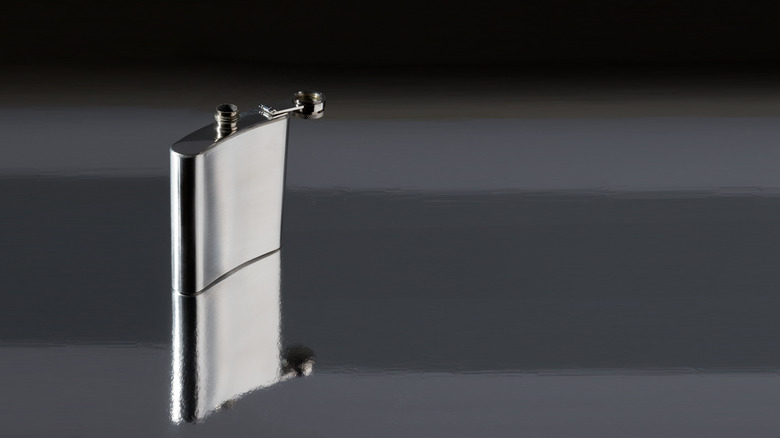 Stainless steel hip flask sitting on mirrored surface