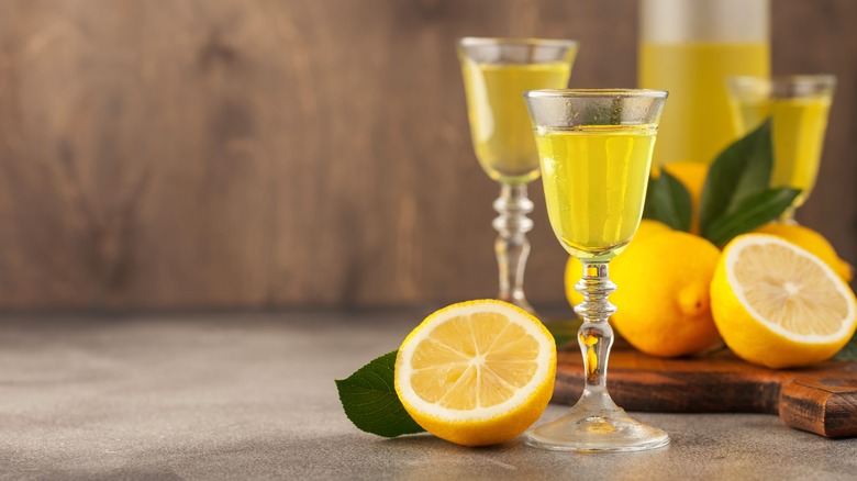 Glasses of limoncello sitting next to lemons sliced in half