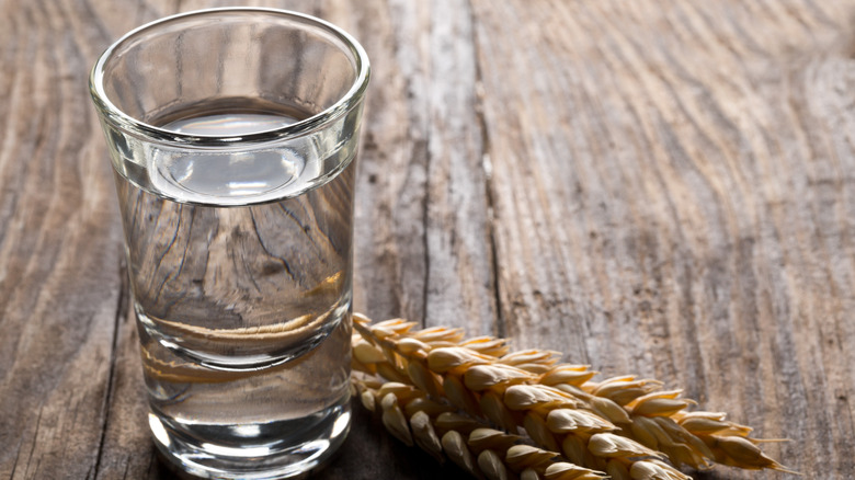 A small glass of clear alcoholic spirit, with some ears of wheat