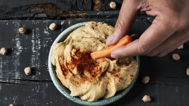 Person dipping carrot in hummus