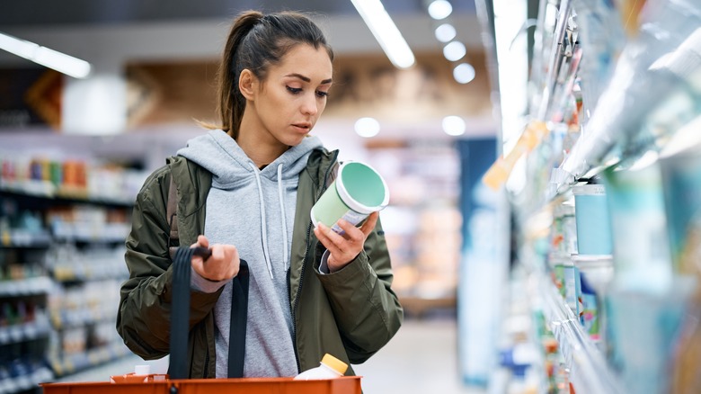 woman examines carton in yogurt aisle