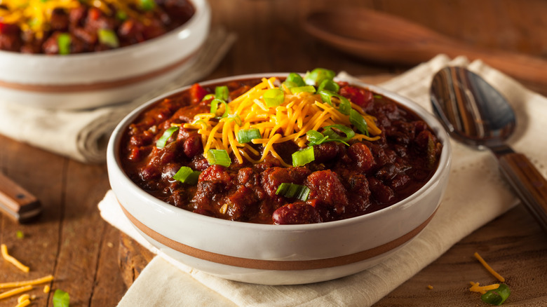 bowl of chili topped with shredded cheese chives 