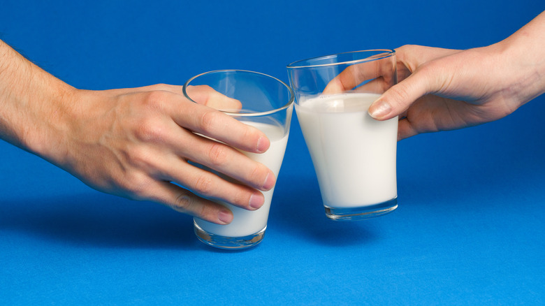 Two people clinking milk glasses