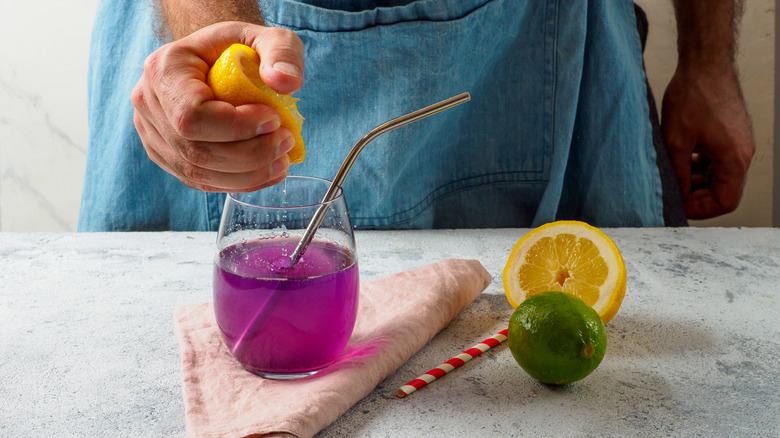 person squeezing lemon into buttterfly pea flower drink