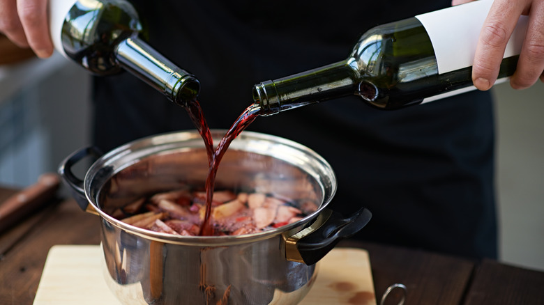 Chef pouring wine into stew