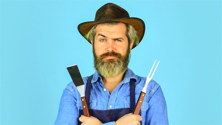 Curious man holding kitchen utensils